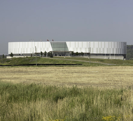 A photo of a circular building with grass in the foreground